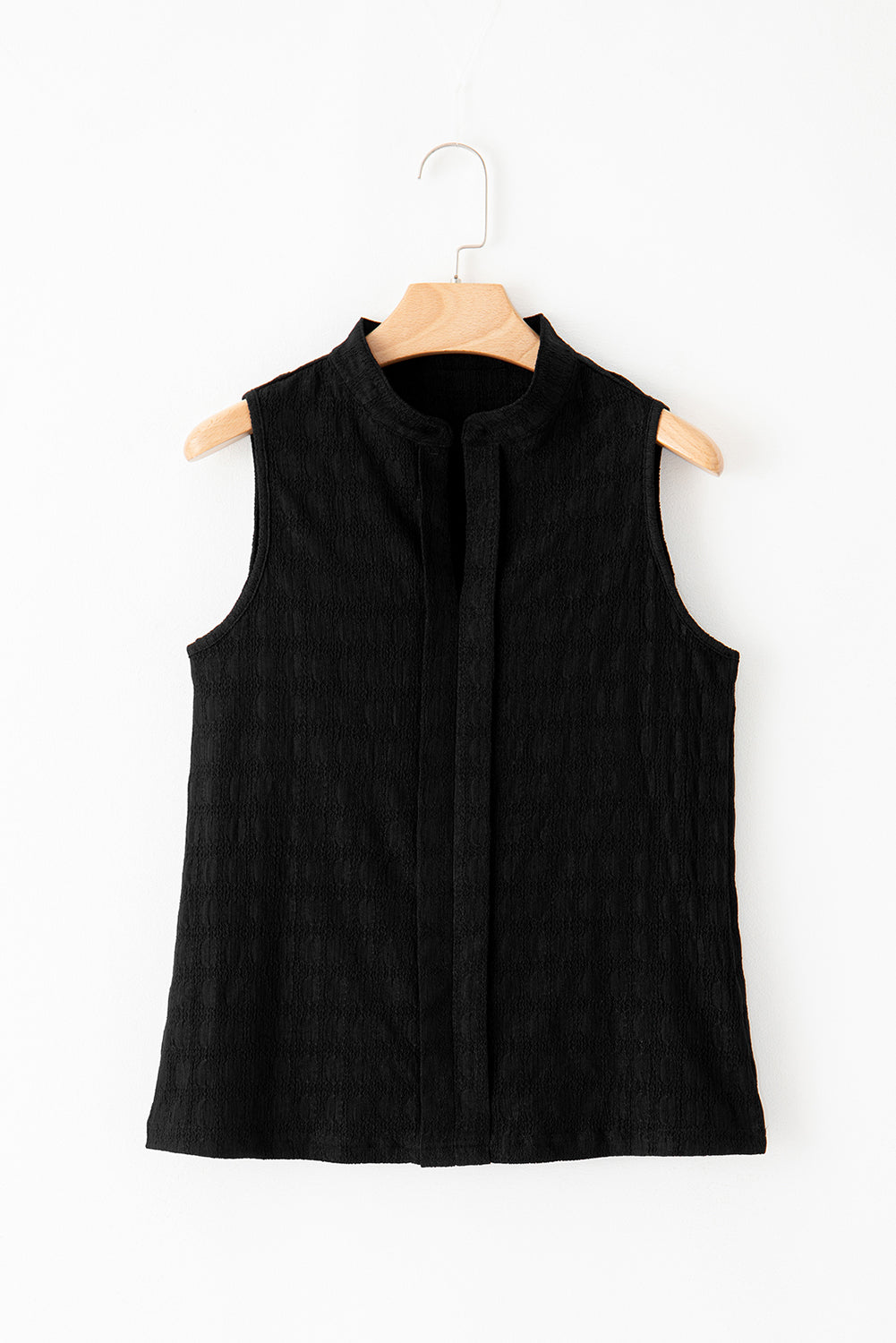 Black sleeveless top on a wooden hanger against a white background
