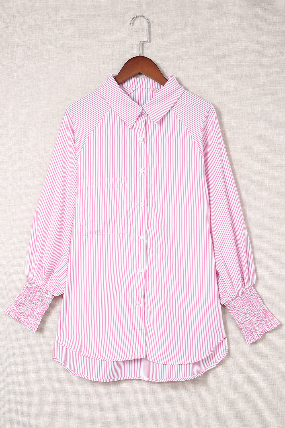 Pink striped shirt on a hanger against a light background