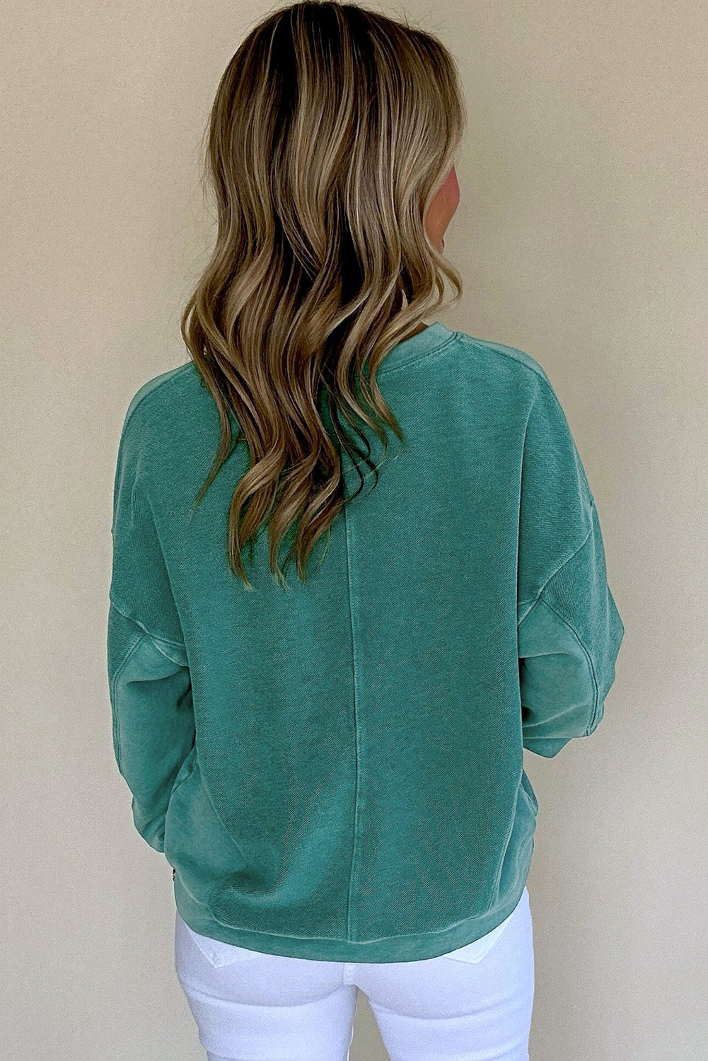 Person wearing a teal sweatshirt with a plain background