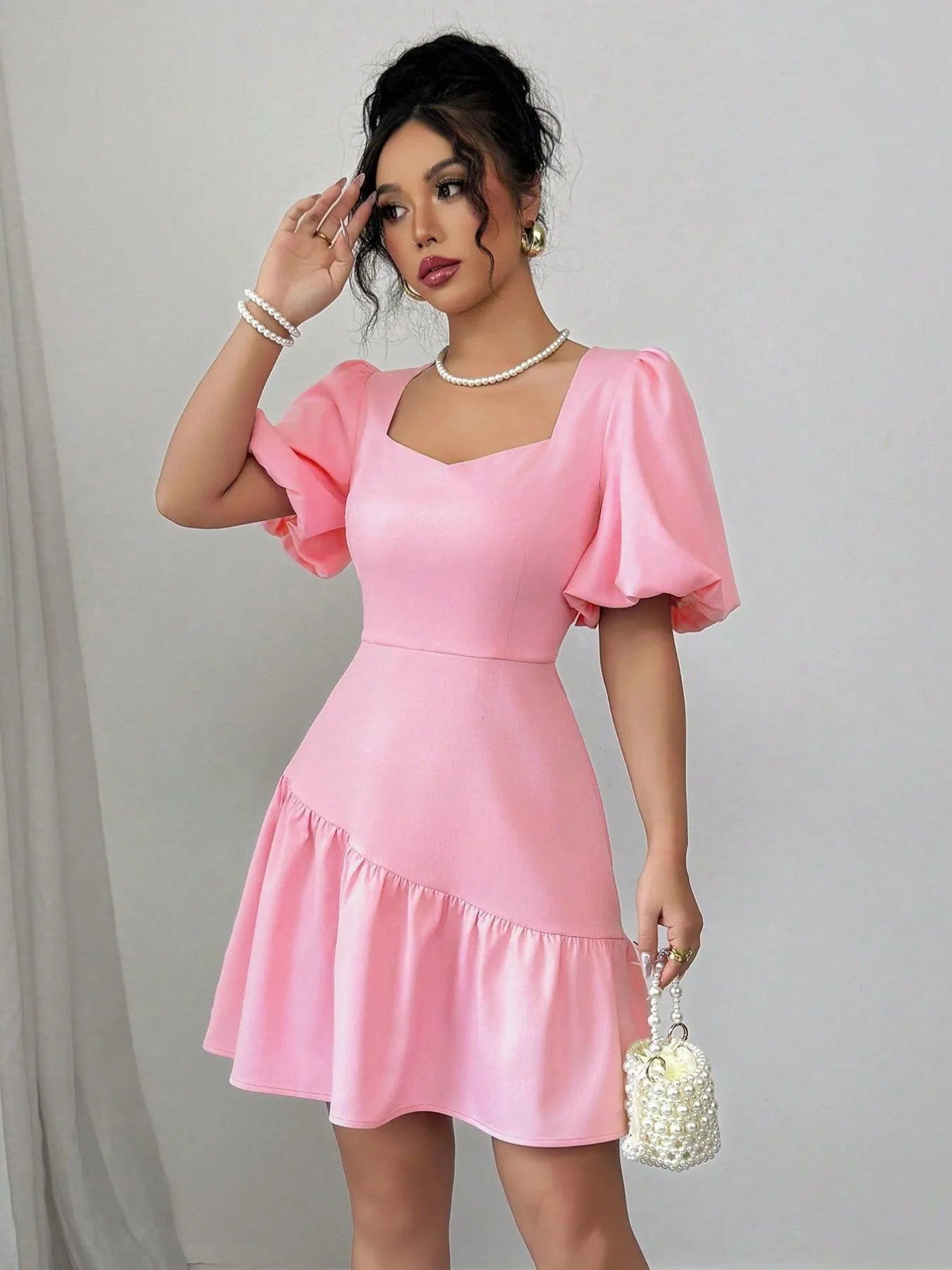 Woman wearing a pink dress with ruffled sleeves against a plain background