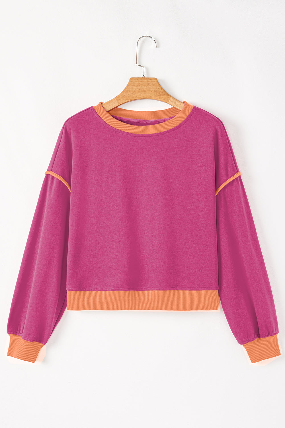 Purple sweatshirt with orange accents on a wooden hanger against a white background