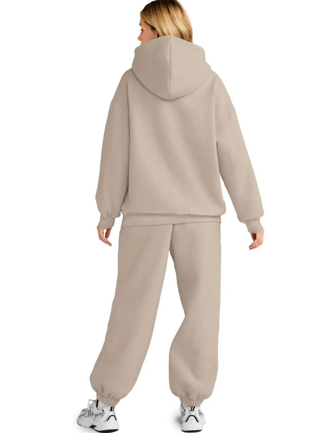 Person wearing a beige tracksuit on a white background