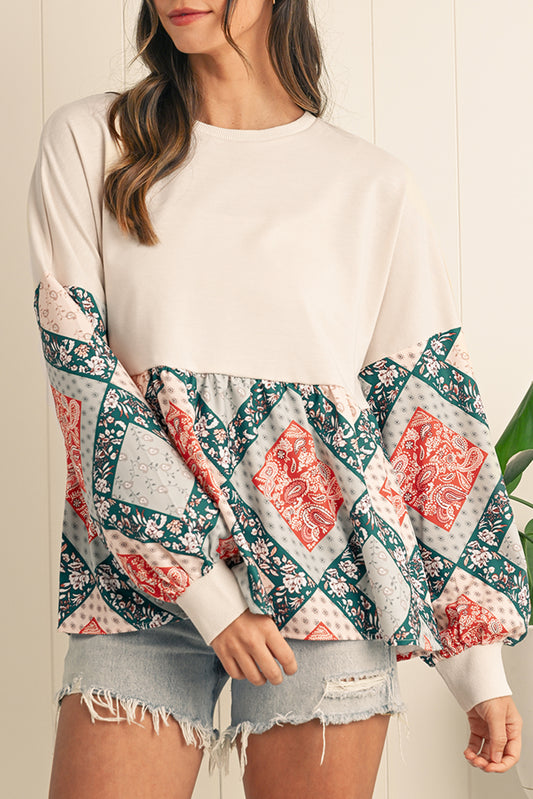 Woman wearing a white sweater with colorful patterned sleeves against a neutral background