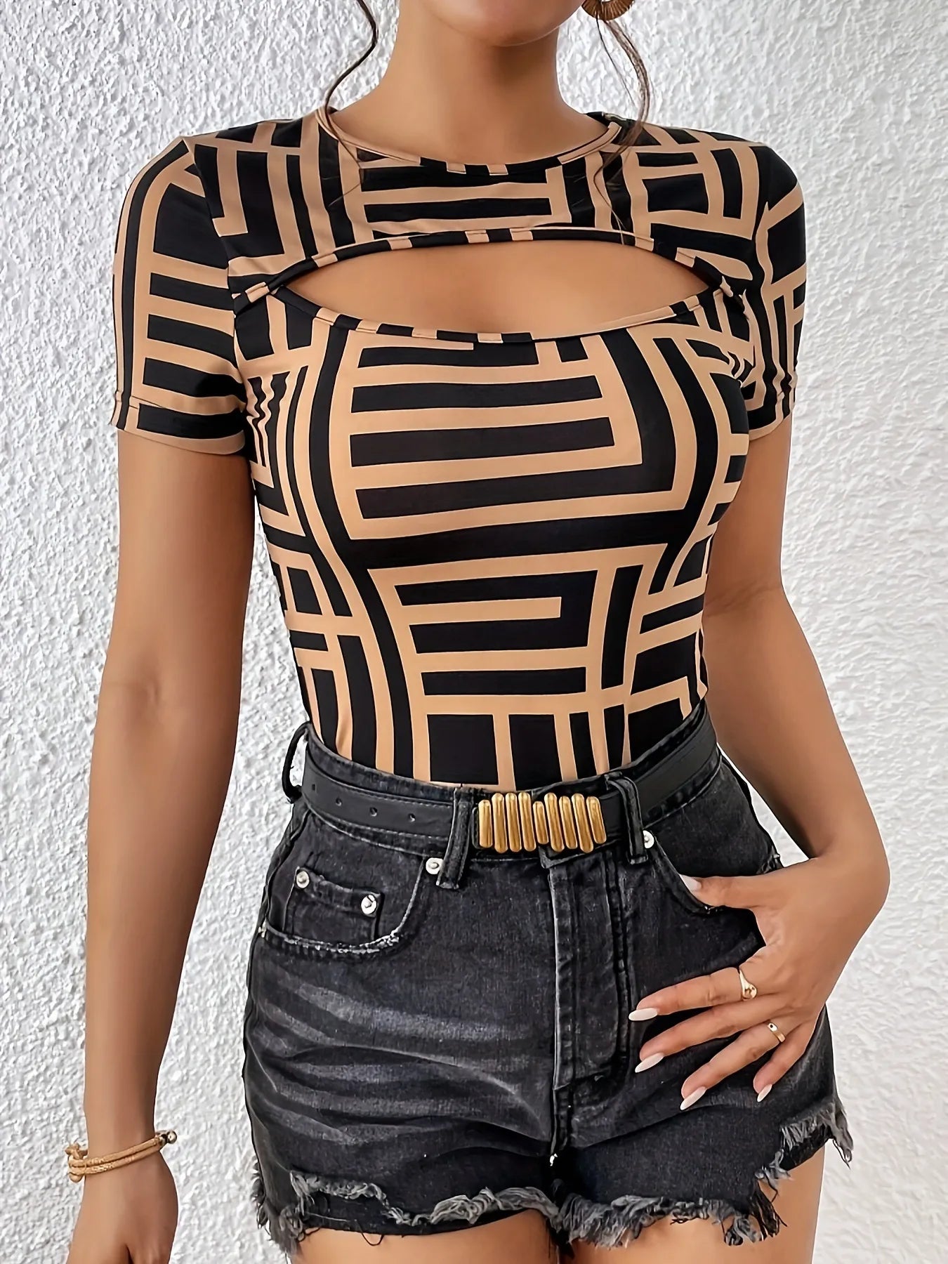 Person wearing a black and beige geometric patterned top with denim shorts on a white background