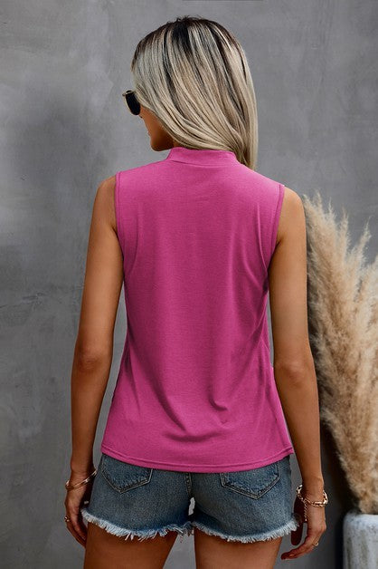 Woman wearing a pink sleeveless top and denim shorts against a gray background