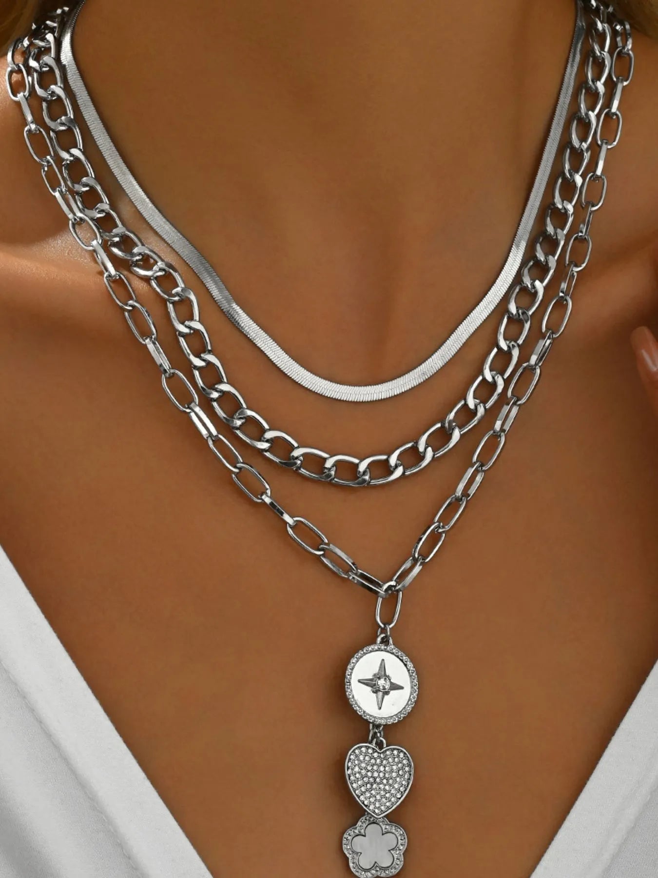 Silver chain necklace with heart and clover pendants on a mannequin.
