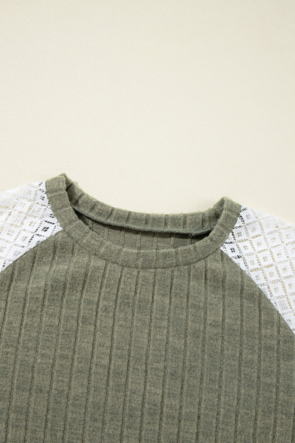 Green ribbed sweater on a textured white surface