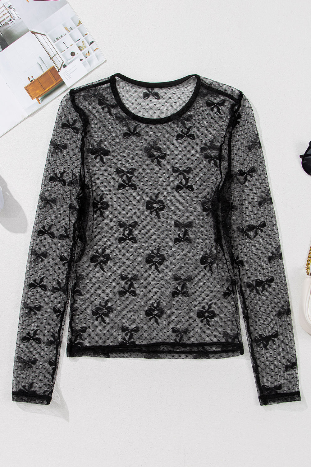 Black lace top with bow pattern on a white surface