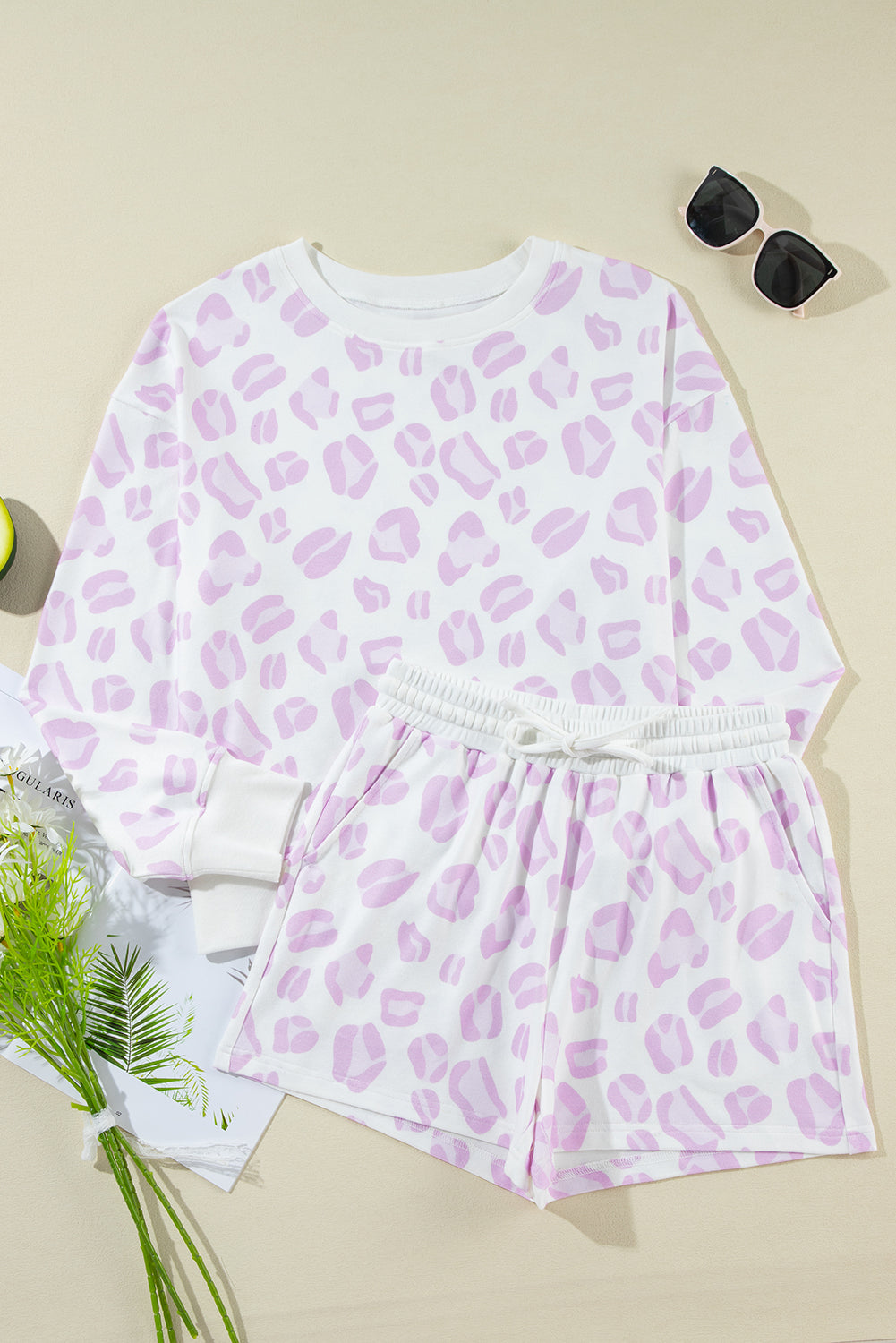 Pink leopard print outfit with sunglasses and flowers on a beige background