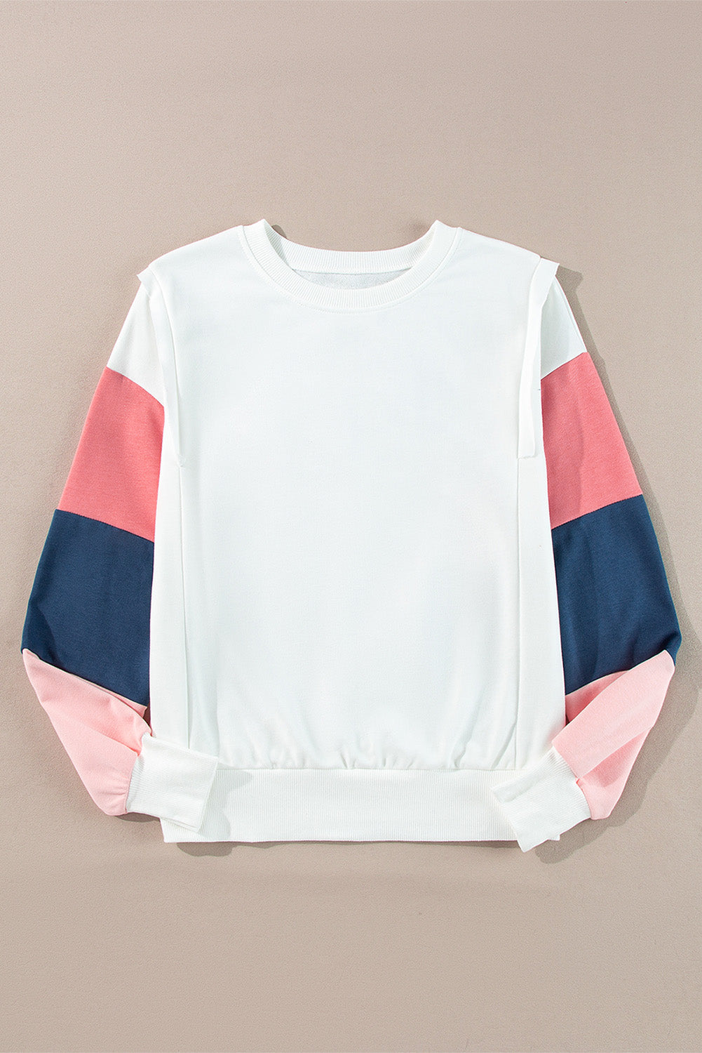 White sweatshirt with pink and blue sleeves on a beige background