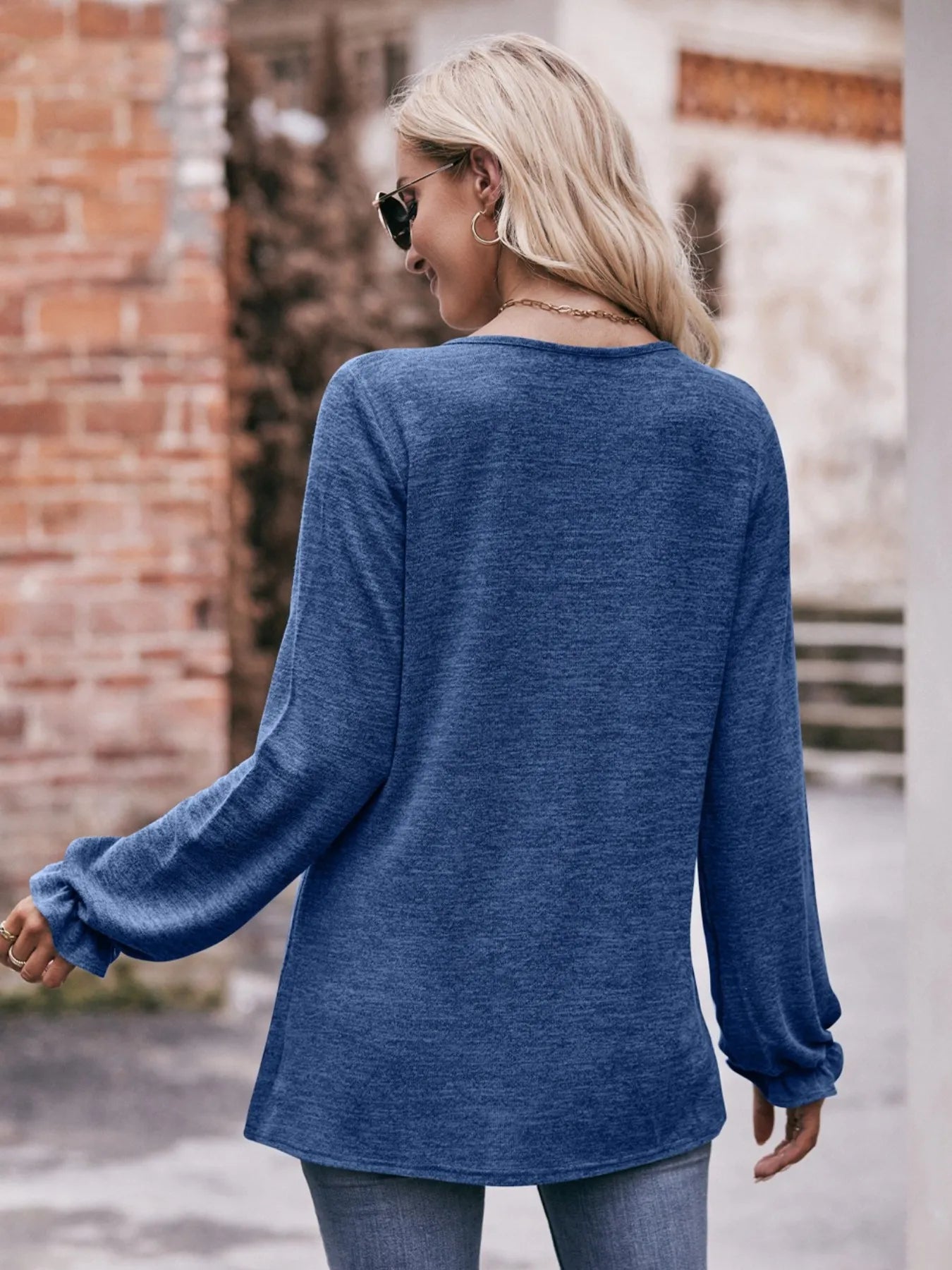 Woman wearing a blue long-sleeve top with a blurred background