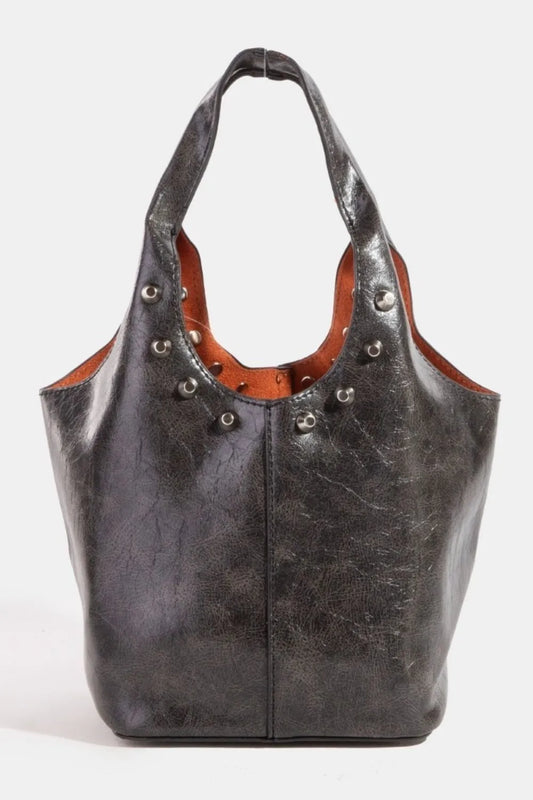 Black leather handbag with brown interior and decorative studs on a white background