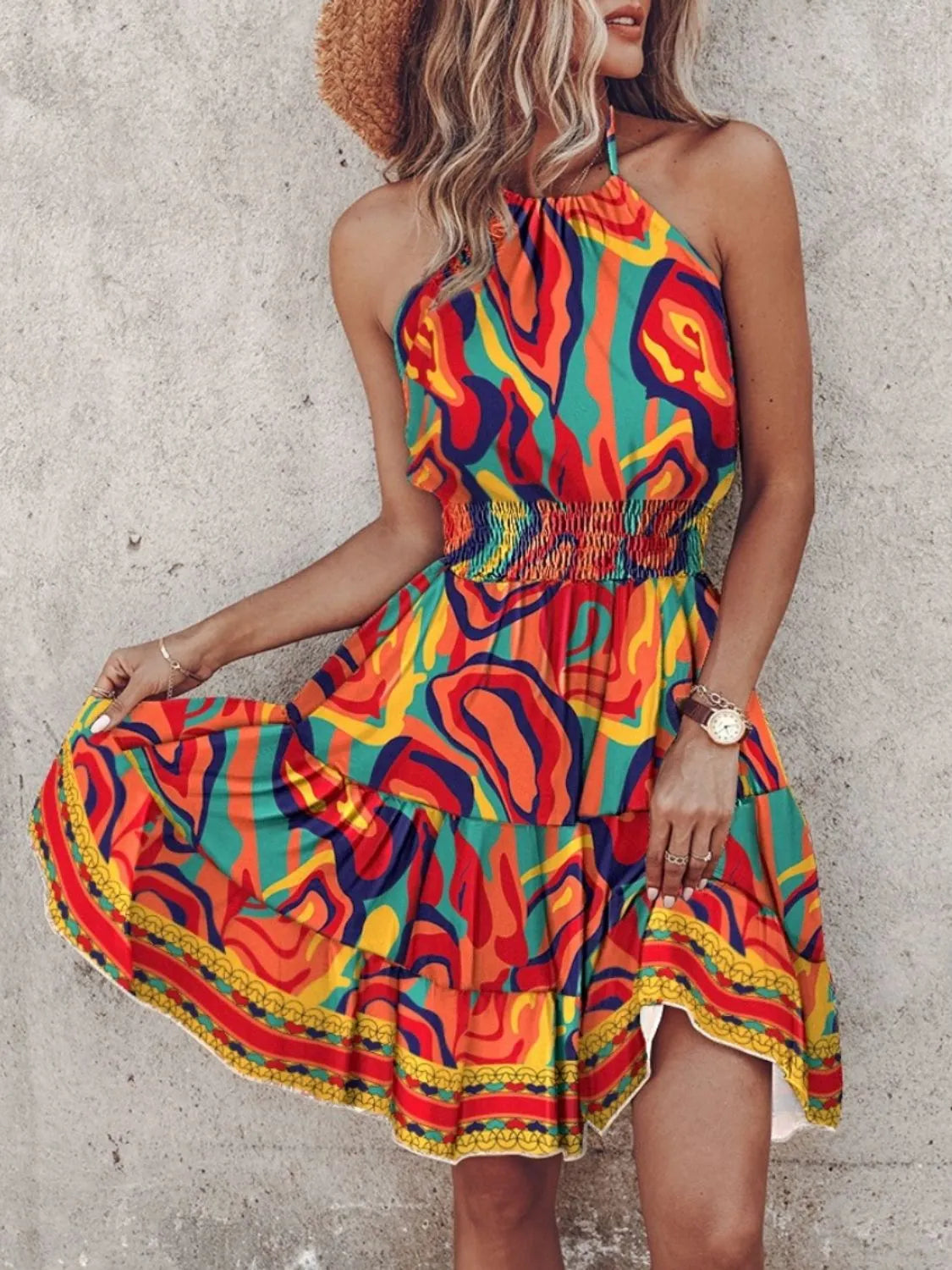 Woman wearing a colorful patterned dress against a concrete wall.