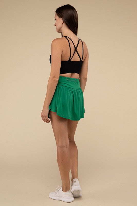 Woman wearing a black sports bra and green skirt on a beige background