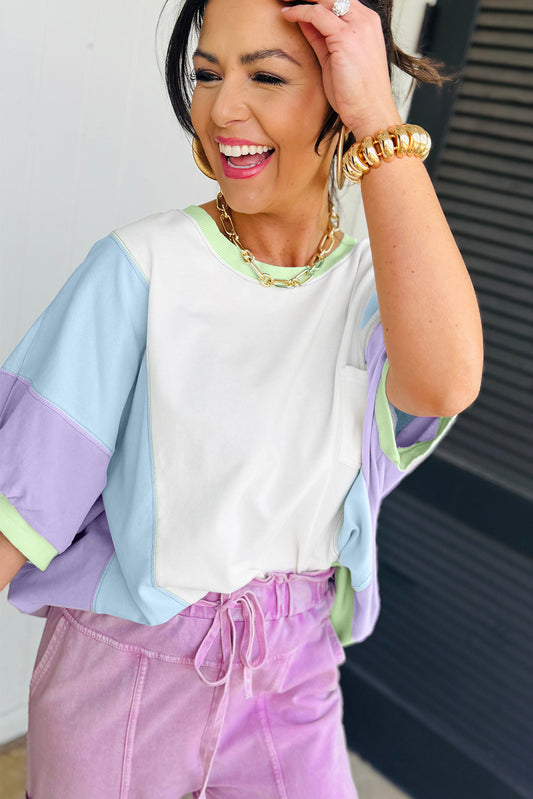 Woman wearing a colorful top and pink pants with a neutral background