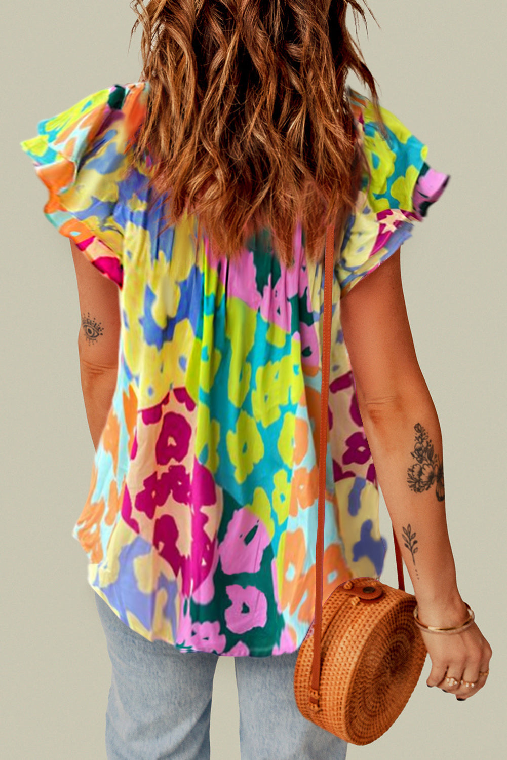 Person wearing a colorful floral dress holding a woven bag against a neutral background