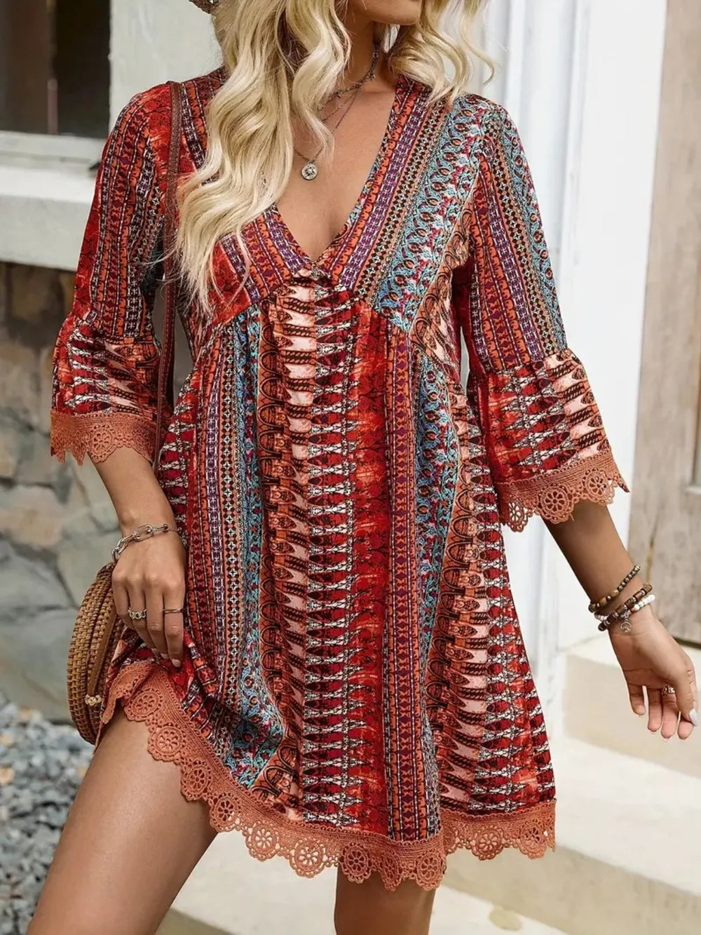 Woman wearing a colorful patterned dress with lace details outdoors.