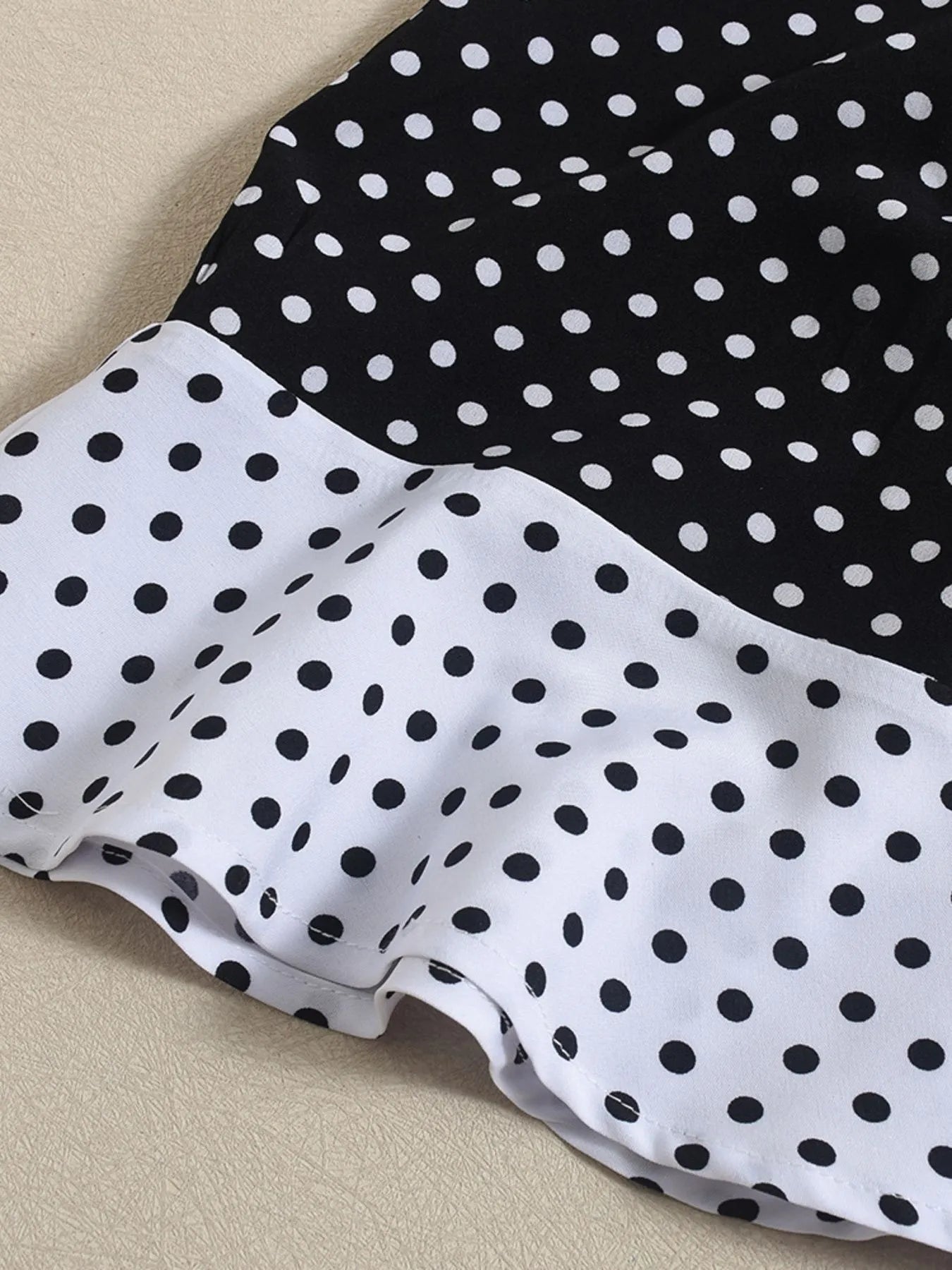 Close-up of a polka dot dress with black and white pattern on a beige surface