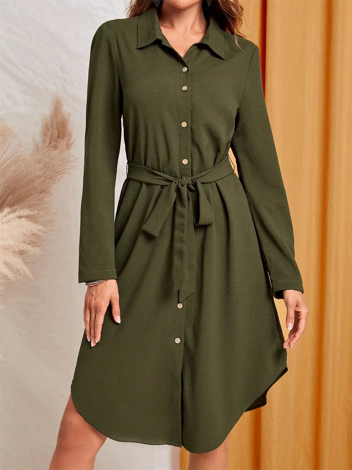 Green dress with a belt on a neutral background