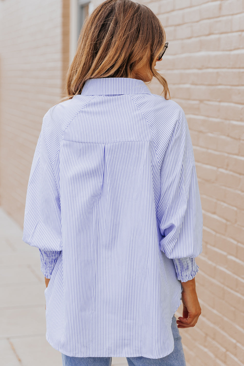 Person wearing a blue and white striped shirt against a beige wall.