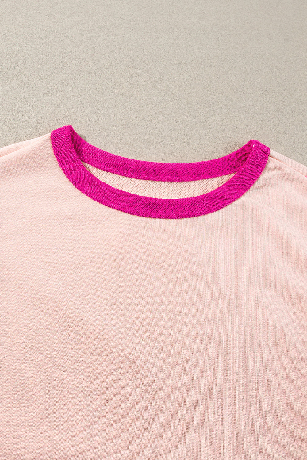 Close-up of a pink shirt with a magenta collar on a neutral background