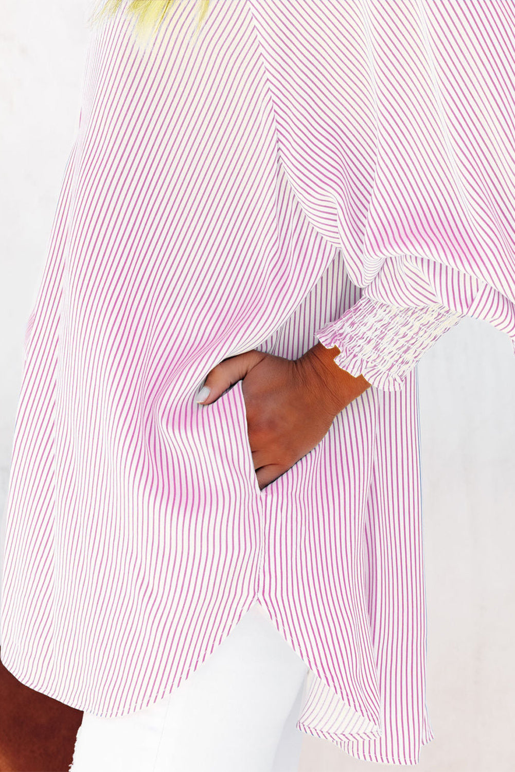 Close-up of a person wearing a pink and white striped shirt with a blurred background