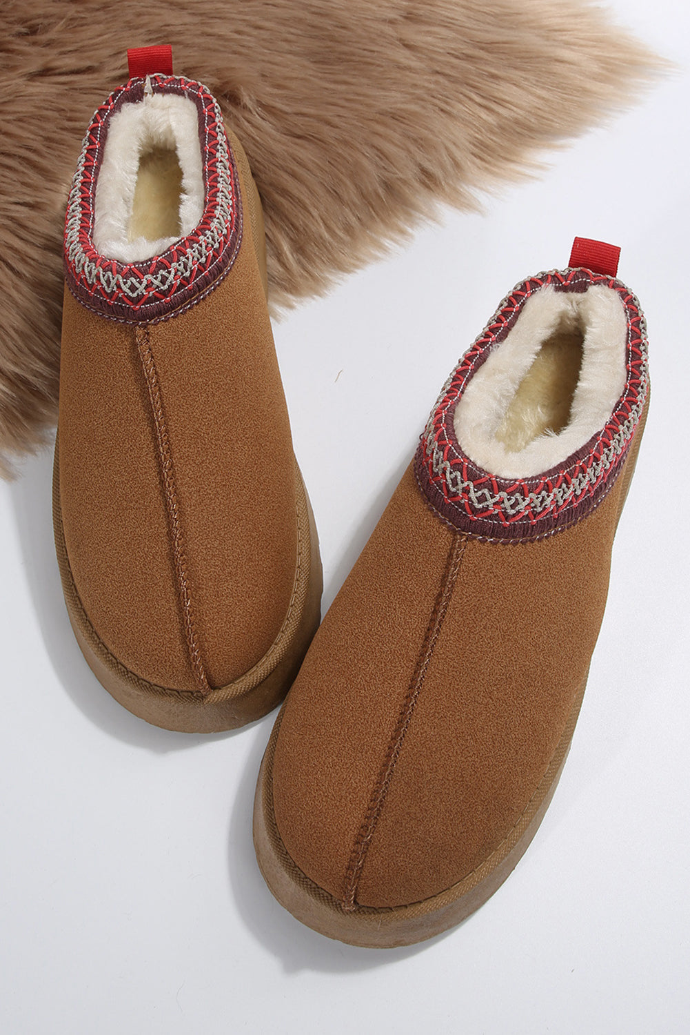 Pair of brown slippers with decorative trim on a white background