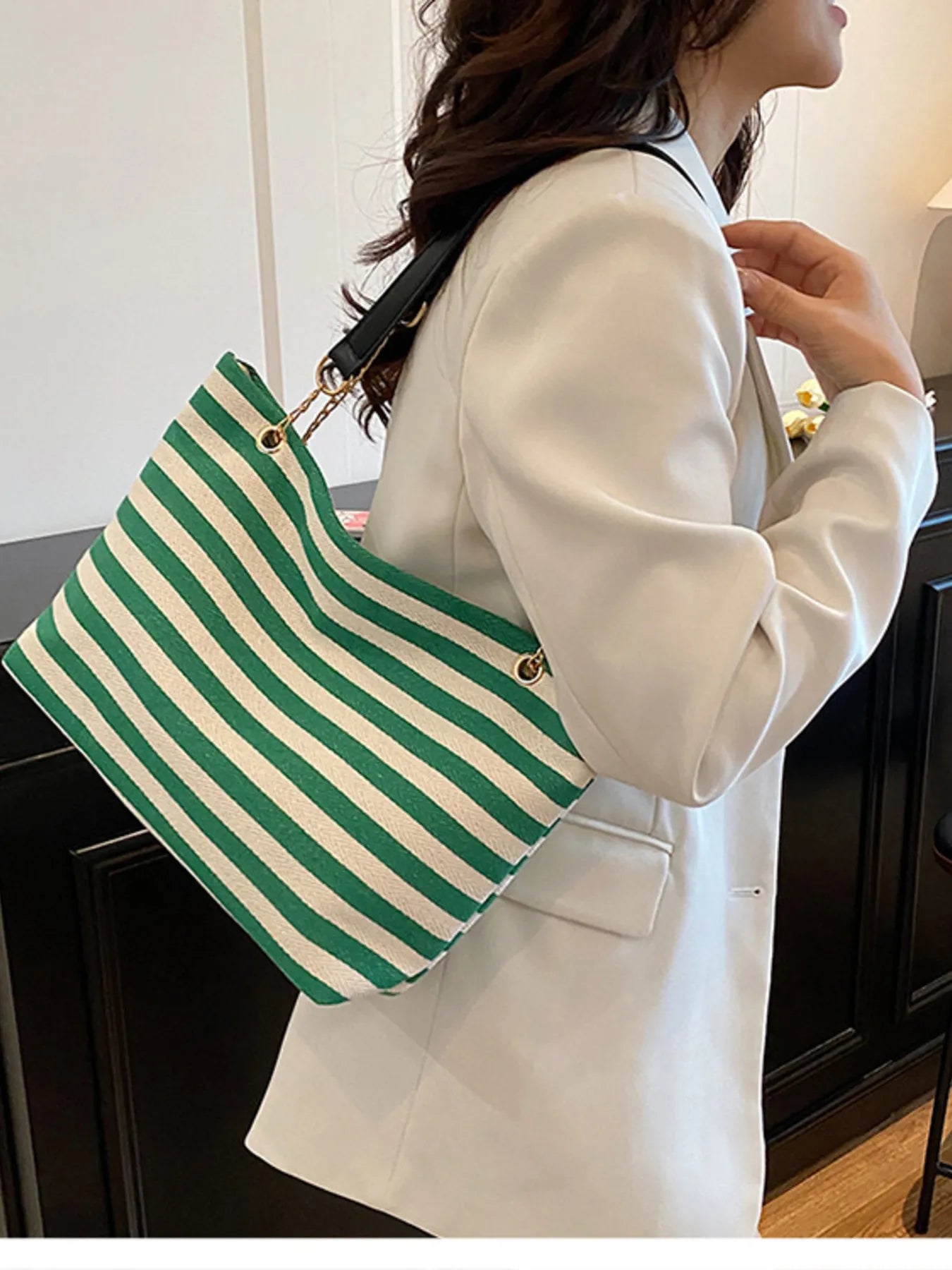 Person wearing a white coat holding a green and white striped bag.
