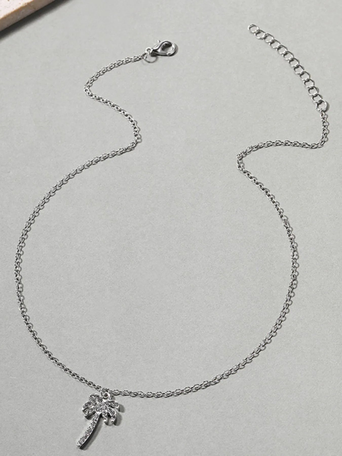 Silver necklace with a small pendant on a gray surface