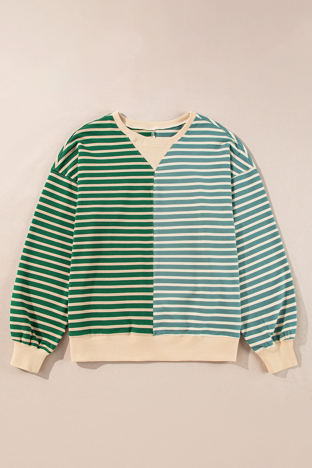 Green and white striped sweater on a beige background