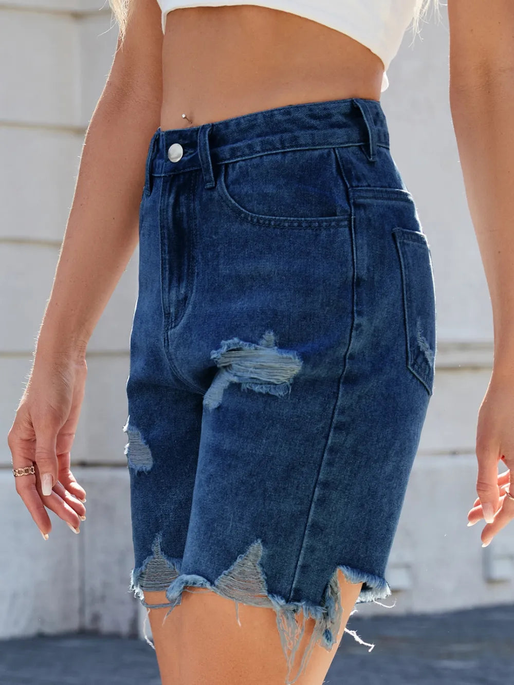 Blue denim shorts with a distressed finish worn by a person.
