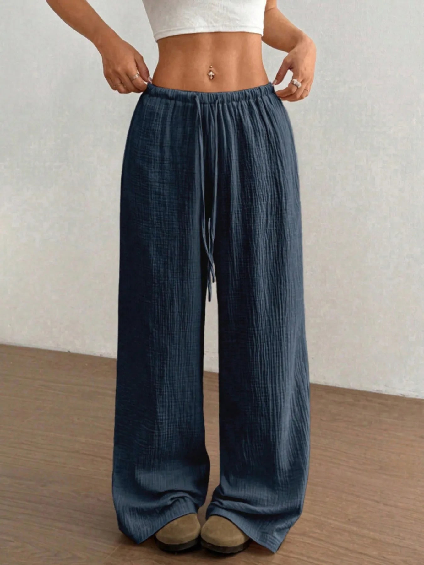 Person wearing blue wide-leg pants with a plain background