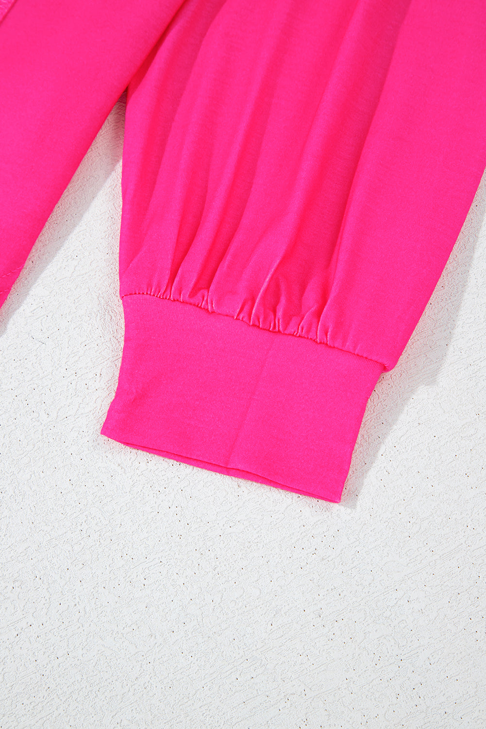 Close-up of a bright pink sweatshirt on a textured white background