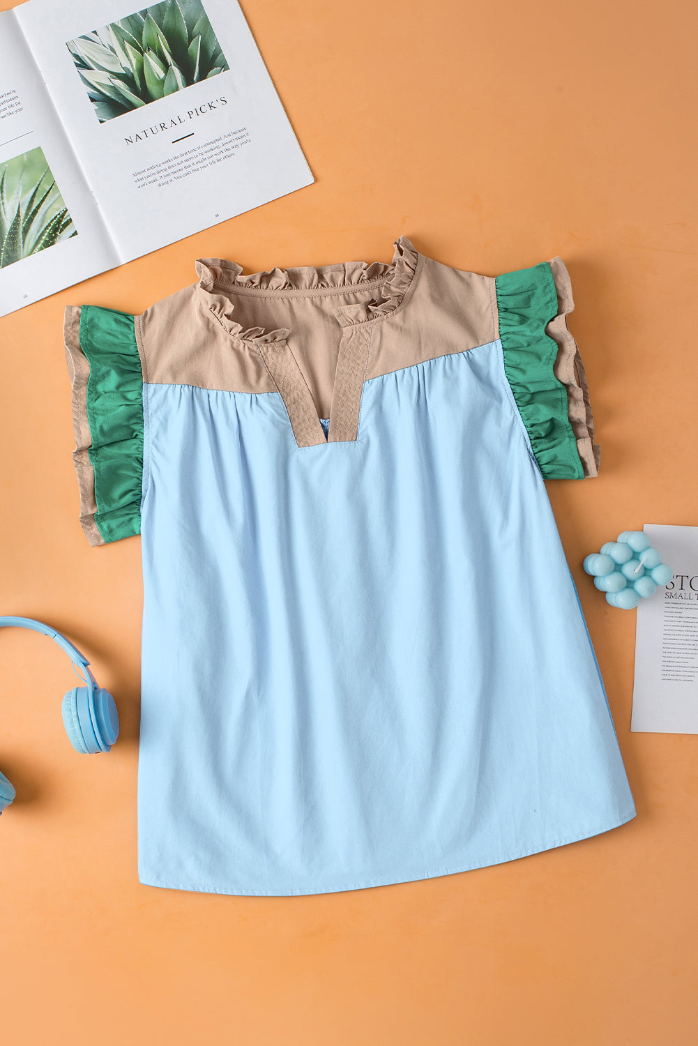 Light blue dress with green and beige accents on an orange background