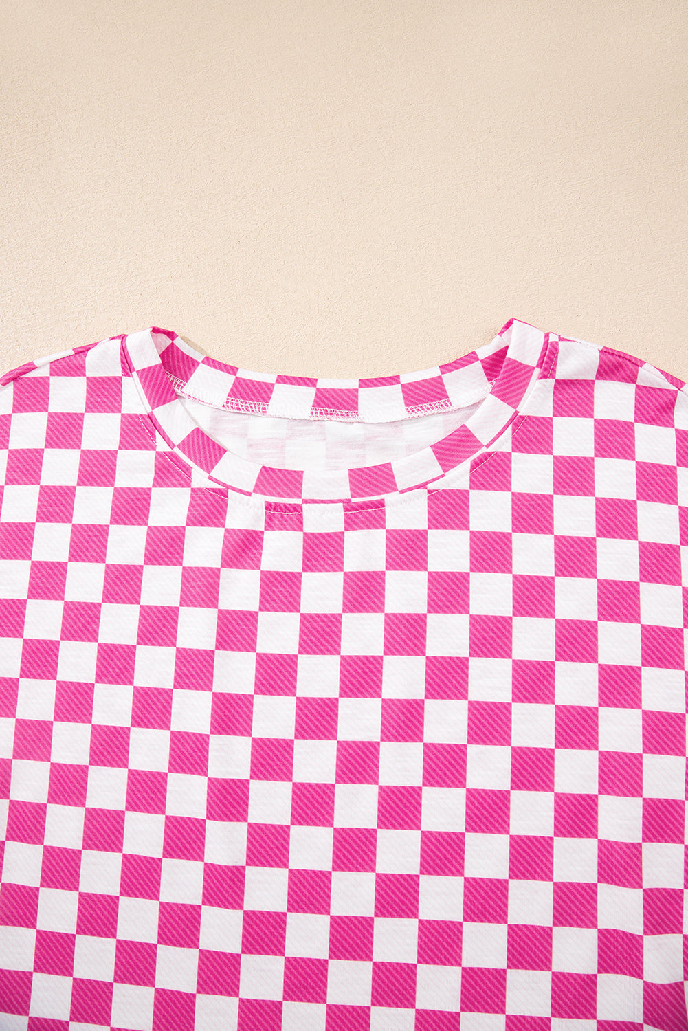 Close-up of a pink and white checkered shirt on a beige background