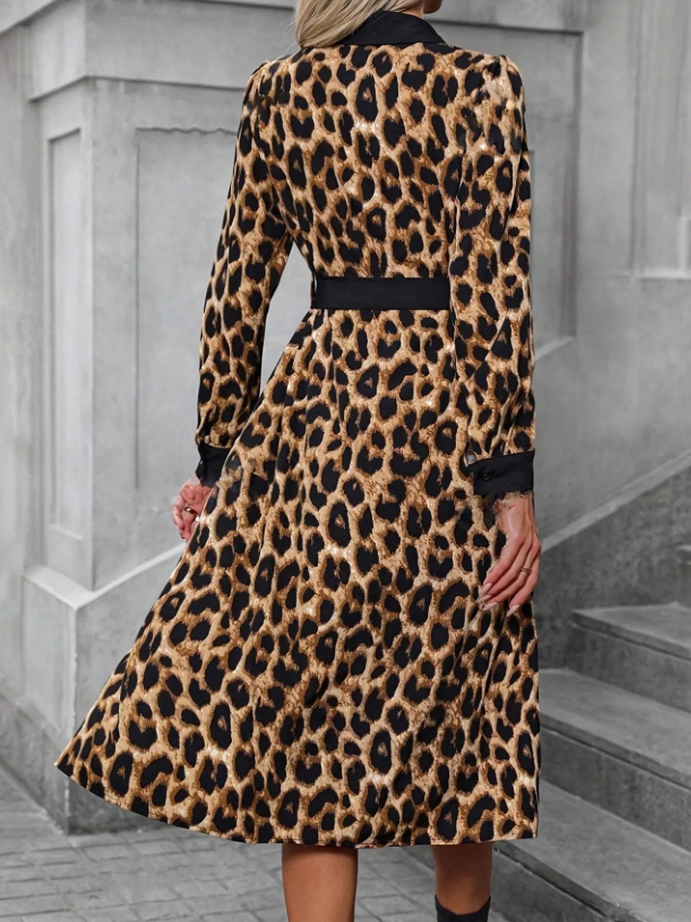 Person wearing a leopard print coat standing on a street.