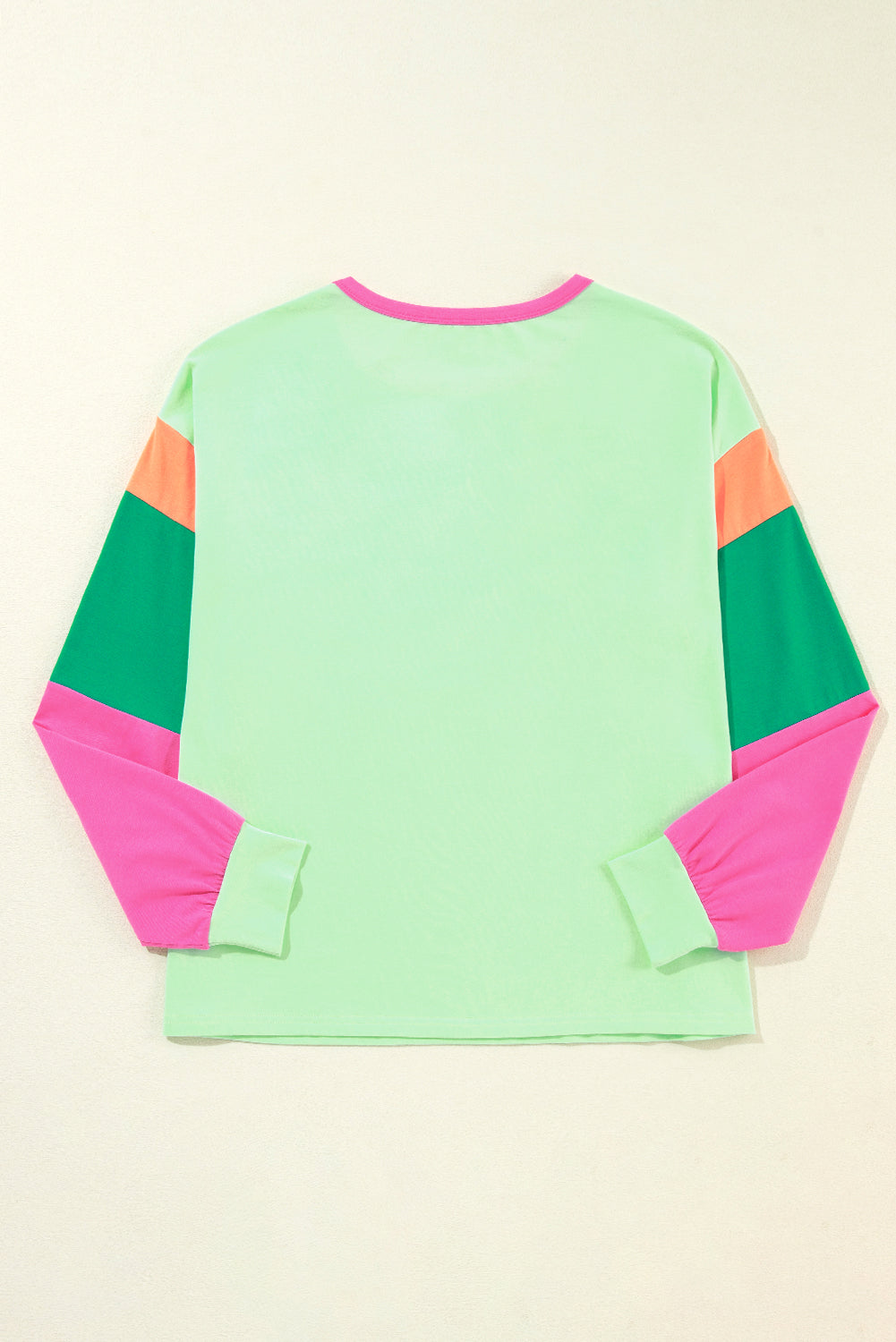 Color-blocked long-sleeve shirt with green, pink, and orange sleeves on a beige background