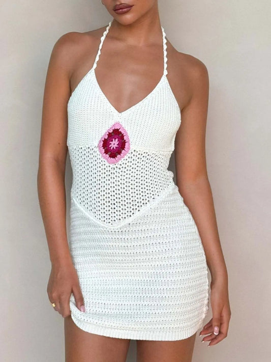 White crochet dress with a pink flower design on a plain background