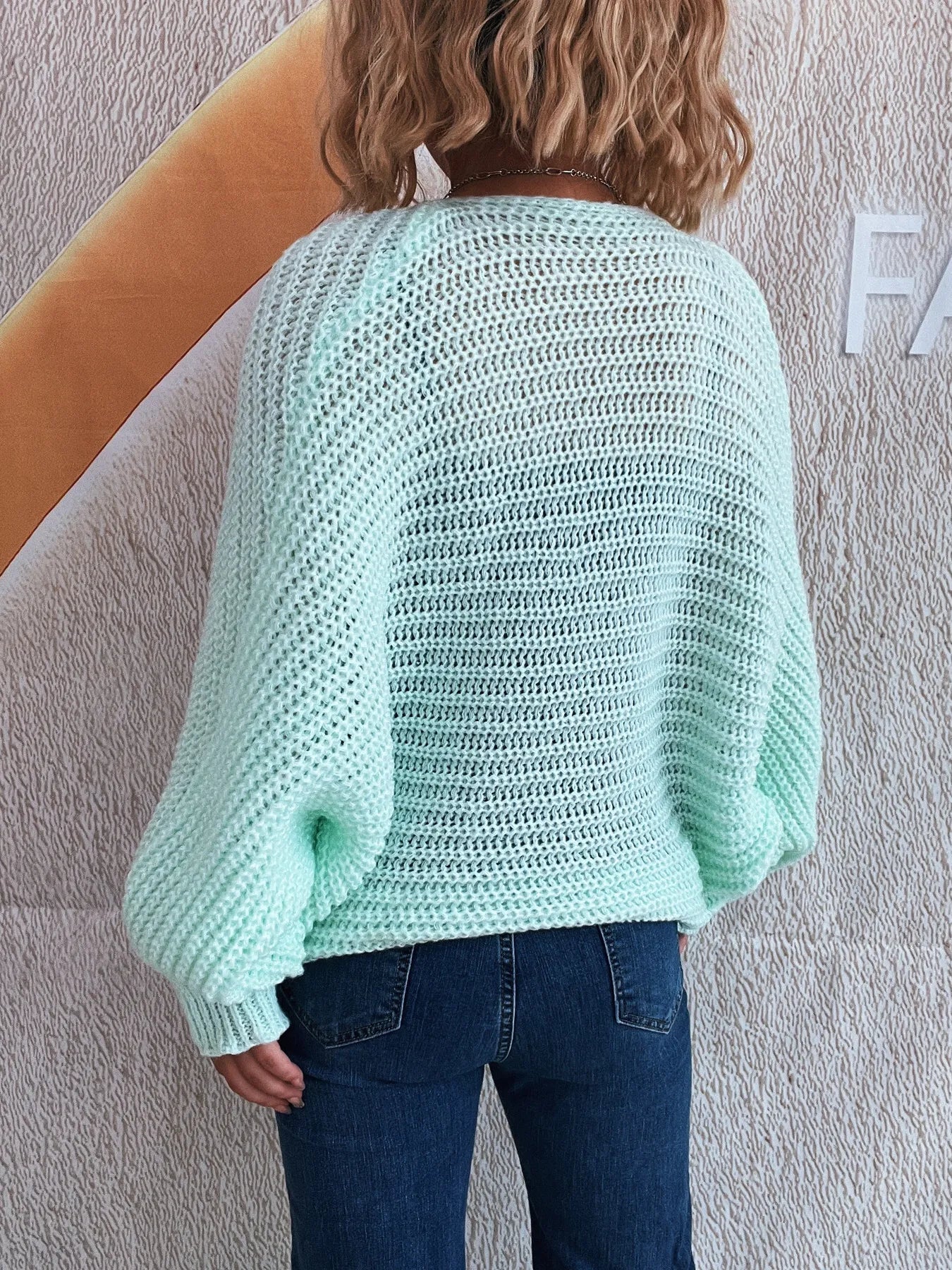 Person wearing a light blue knitted sweater against a plain background
