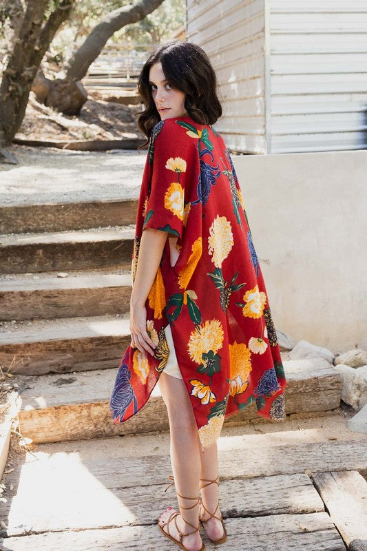 Woman wearing a red floral dress standing on wooden steps outdoors.