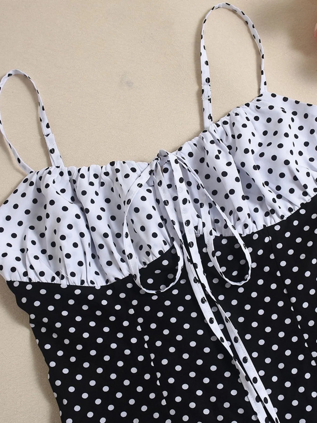 Black and white polka dot dress with thin straps on a beige background