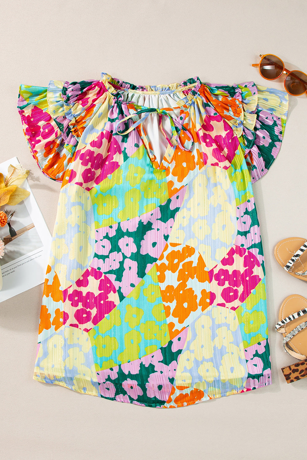 Colorful floral dress on a light background with sunglasses and sandals.