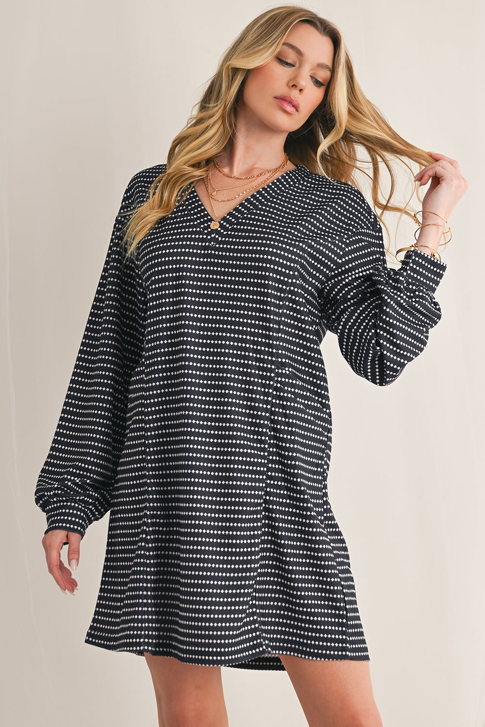 Woman wearing a black and white patterned dress against a beige background