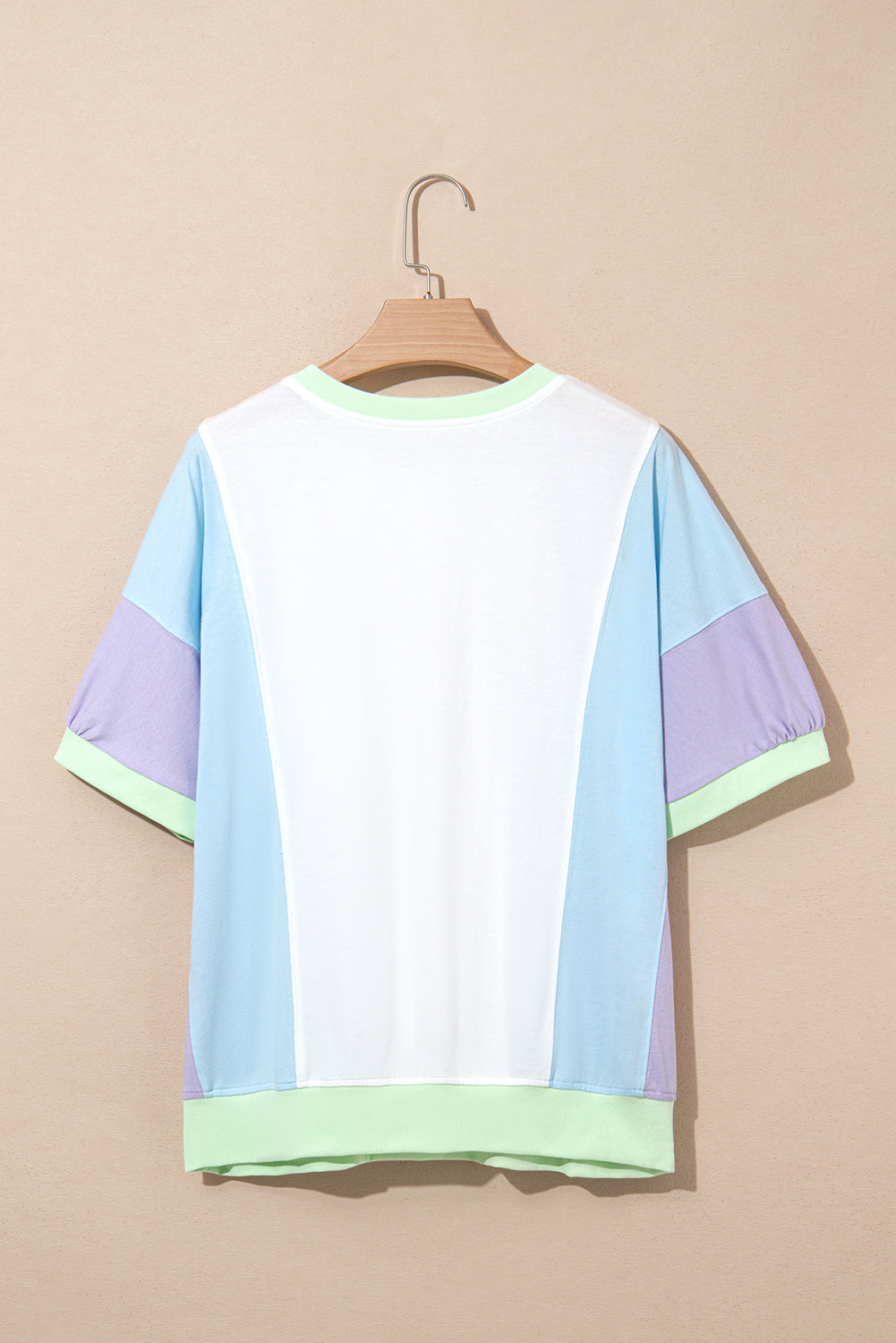 Color-blocked t-shirt on a hanger against a beige background