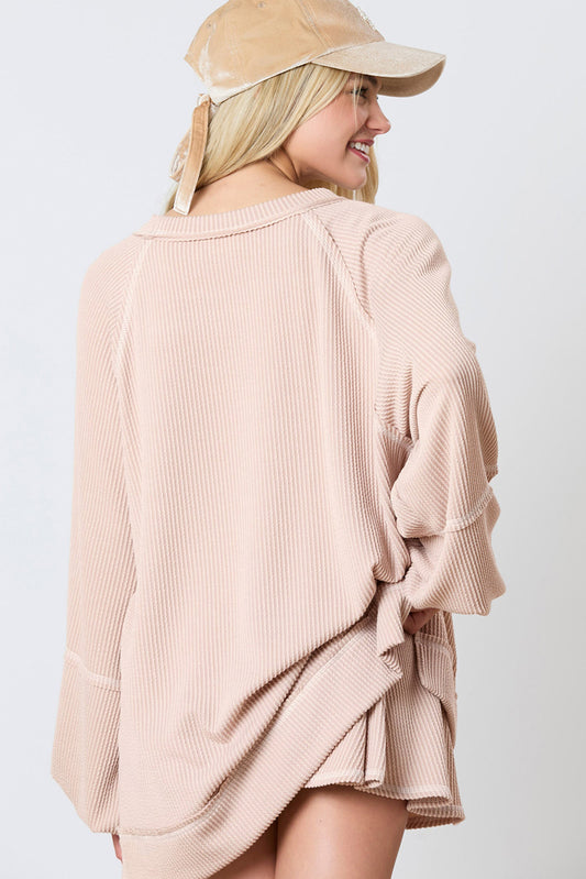 Woman wearing a beige ribbed sweater and cap on a white background