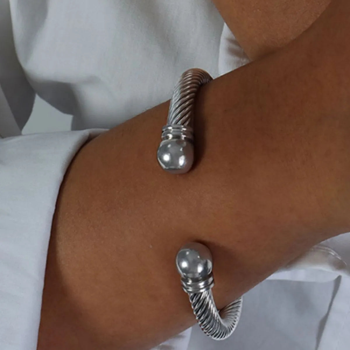Silver bracelet on a wrist with a white background