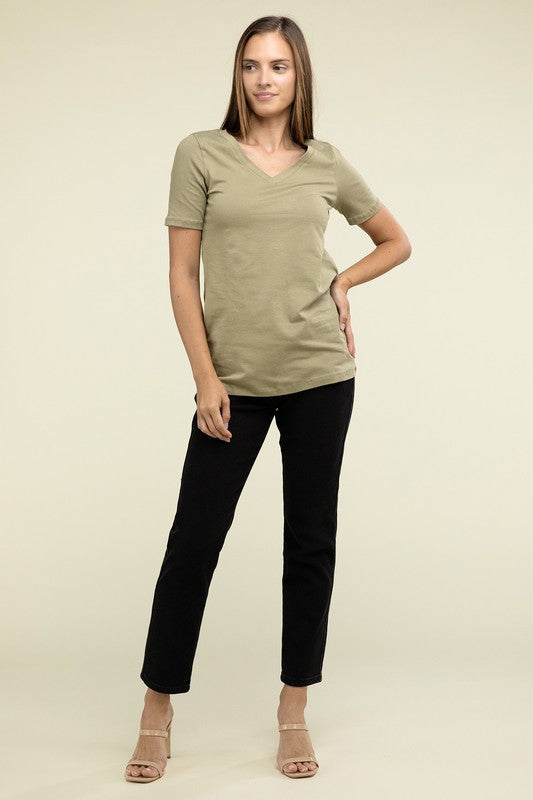 Woman wearing a green top and black pants on a beige background