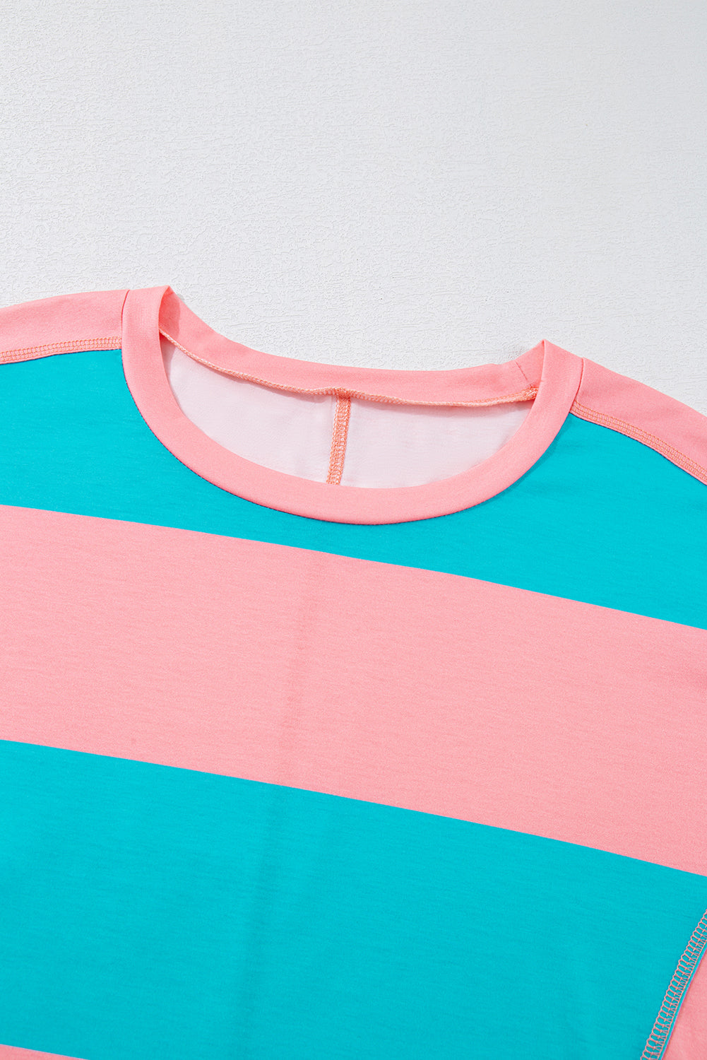 Close-up of a shirt with pink and teal stripes on a light gray background