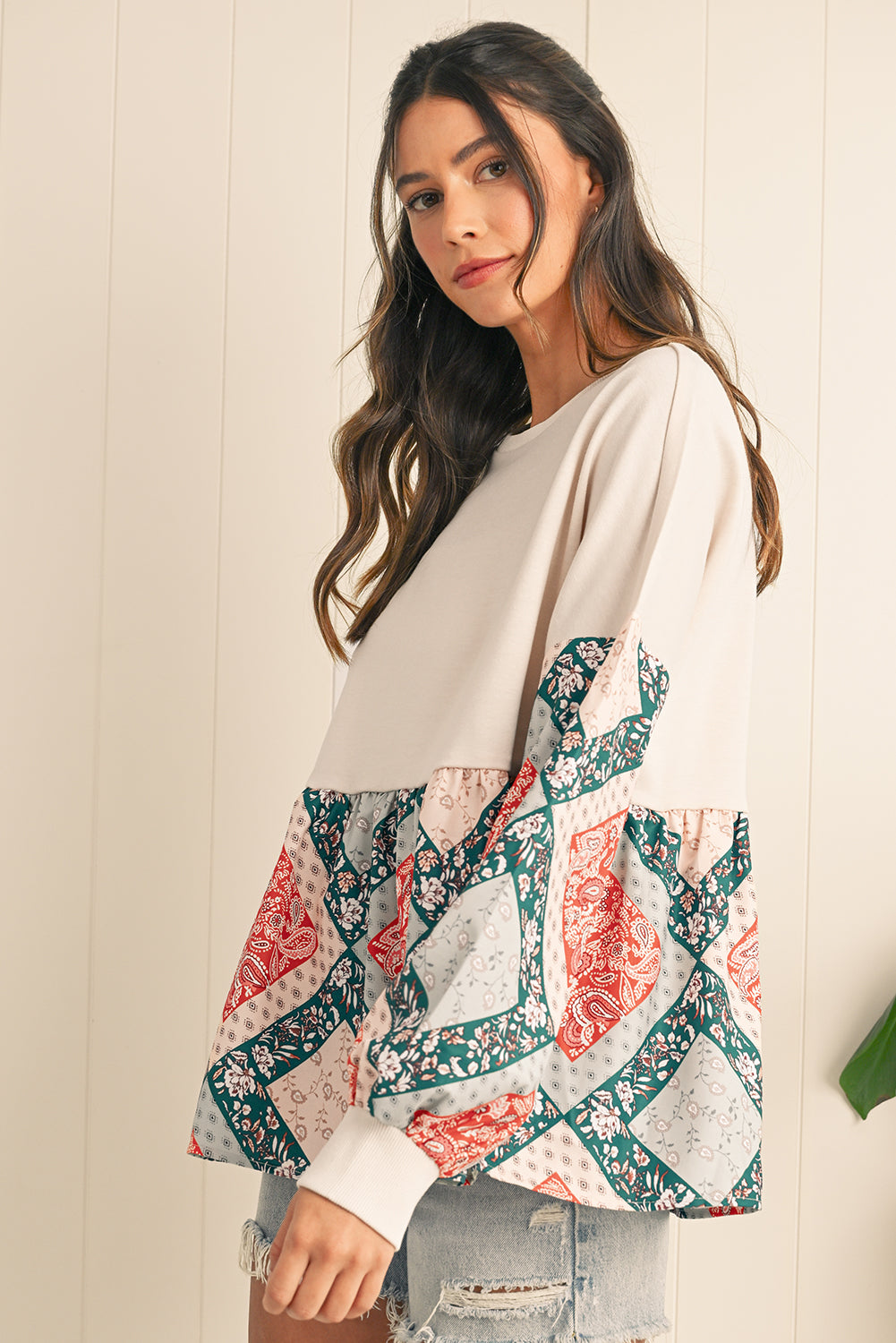 Woman wearing a patterned top with a neutral background