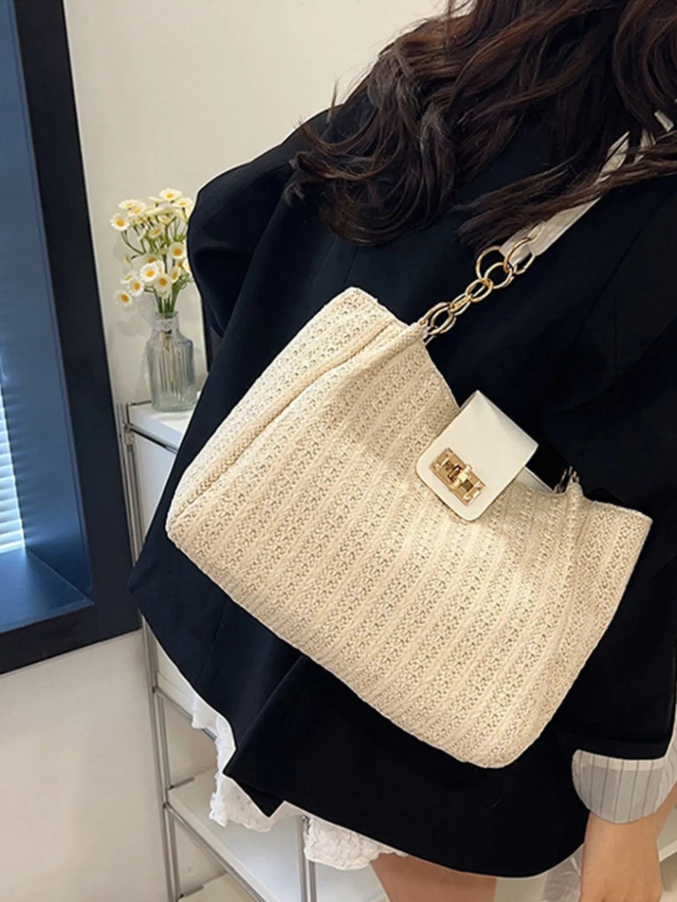 Person wearing a beige textured handbag with a gold chain strap.